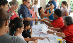 Members of the Episcopal Diocese of Central Florida's abuelita volunteer program and a church member work together to sign in community members for the Back to School Bash.